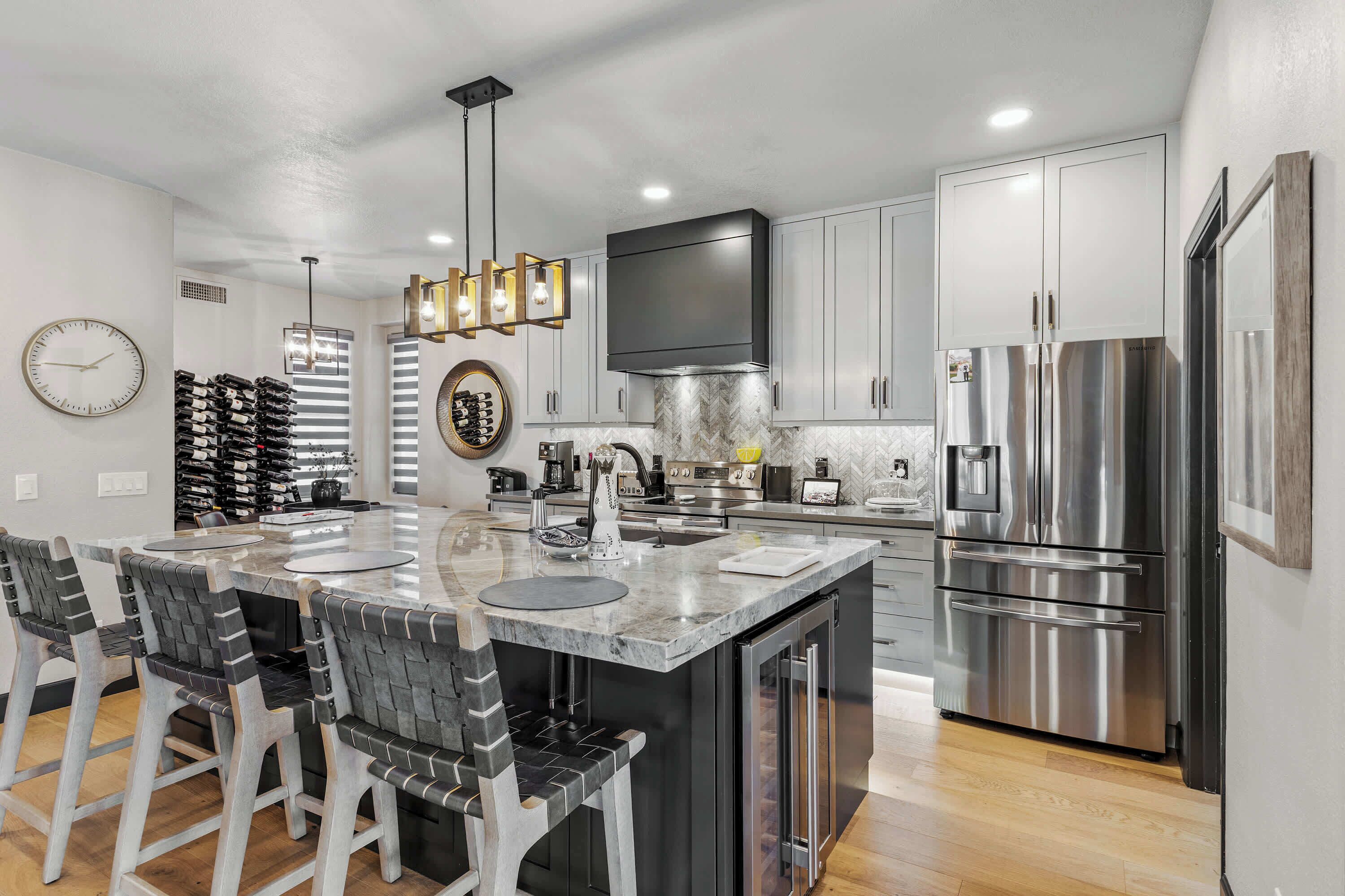 A modern kitchen with a central island, stainless steel appliances, and a clock on the wall.