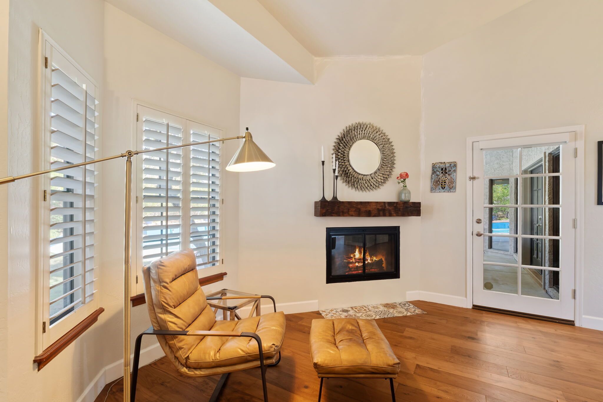 Una sala de estar con chimenea, un sillón, una lámpara de pie y una puerta.