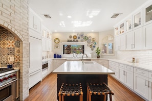 A modern kitchen with white cabinetry, a central island, and a backsplash with patterned tiles. - Pyra - Private Pool - Mins to Kierland Commons (Scottsdale)