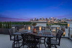 An outdoor dining area with a city skyline view, a table with chairs, and candles. - Elevated Luxury • Amazing Rooftop Views W/Elevator (Nashville)