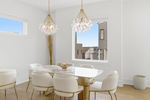 A dining area with a white table, gold chairs, and a chandelier. - Elevated Luxury • Amazing Rooftop Views W/Elevator (Nashville)