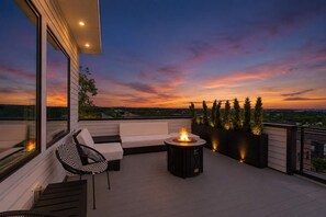 A rooftop terrace with a sofa, a chair, a fire pit, and potted plants. - Elevated Luxury • Amazing Rooftop Views W/Elevator (Nashville)