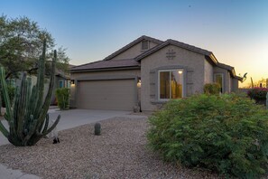 A single-story house with a garage, surrounded by a gravel driveway, cacti, and shrubs. - The Retreat at Gold Canyon - Private Pool, Firepit & Superstition Mountain Views (Gold Canyon)