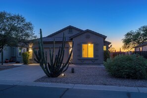 A residential house with a well-maintained garden, including a large cactus, at dusk. - The Retreat at Gold Canyon - Private Pool, Firepit & Superstition Mountain Views (Gold Canyon)