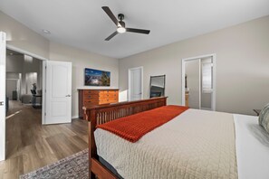 A bedroom with a bed, a ceiling fan, a dresser, and a door leading to another room. - The Retreat at Gold Canyon - Private Pool, Firepit & Superstition Mountain Views (Gold Canyon)