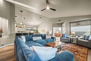 A modern living room with a sectional sofa, a coffee table, and a ceiling fan. - The Retreat at Gold Canyon - Private Pool, Firepit & Superstition Mountain Views (Gold Canyon)