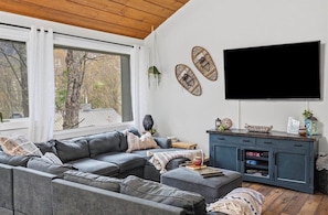Ein modernes Wohnzimmer mit einer Eckcouch, einem Flachbildfernseher und einem blauen Schrank.