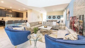 A spacious living area with a sofa, armchairs, a coffee table, and a kitchen in the background. - 5 Star Villa with Pool & Spa and Game Room! (Kissimmee)