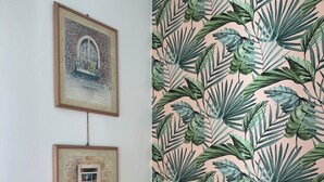 A room with a patterned wallpaper, two framed pictures on the wall, a desk lamp, and a wooden headboard. - Vintage cottage near the sea (Riccione)