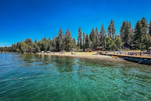 Ein Seehotel mit klarem Wasser, einer Anlegestelle und bewaldeter Uferlinie.