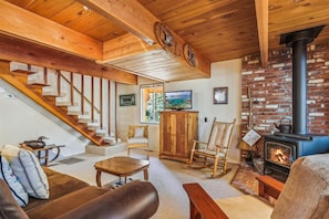 Ein gemütliches Wohnzimmer mit Kamin, einer Holztreppe und bequemen Sitzgelegenheiten.