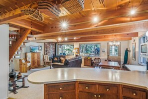 Ein rustikales Interieur mit einer großen Holzbalkendecke, einem Kamin aus Stein und einem Essbereich mit großem Tisch und Stühlen.