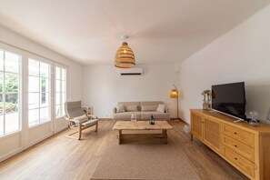 Ein geräumiges Wohnzimmer mit einer Couch, einem Couchtisch, einem Fernseher und einem großen Fenster.