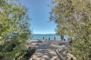 A wooden pathway leading to a beach with people walking and sitting. - Carnelian Woods # 108 by Tahoe Getaways - Pet-Friendly 3BR with HOA Pool & Lake Access (Carnelian Bay)