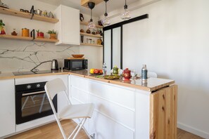 Une cuisine compacte équipée d’un four à micro-ondes, d’un four traditionnel, d’un plan de travail en bois et de meubles blancs.