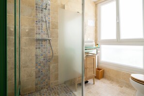 Une salle de bain avec douche, toilettes et lavabo.