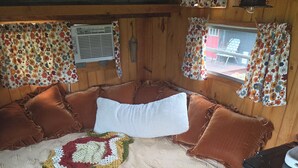 A cozy room with a large bed, a wooden headboard, a small table, and a black cabinet. - Serene recreational vehicle with AC in charming Springdale (Springdale)