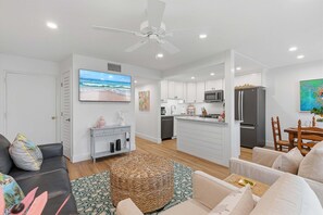 Ein modernes Wohnzimmer mit Sofa, Hocker und Flachbildfernseher.