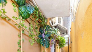 A narrow hallway with yellow walls, a patterned floor, and green plants. - Cozy Studio in Santo Domingo Este With Modern Amenities (Santo Domingo Este)