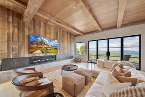 Ein modernes Wohnzimmer mit Kamin, großen Fenstern und einem schönen Ausblick.