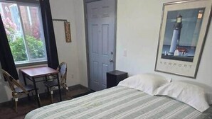 Une pièce comprenant un lit, un bureau, une chaise, une porte et un tableau encadré accroché au mur.