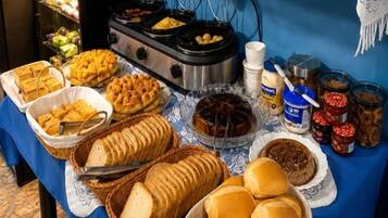 Una mesa de buffet con diversos alimentos, como pan, bollería y salsas.