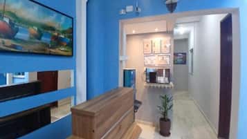 Un área de recepción con un mostrador de madera, una planta en maceta y cuadros en la pared.
