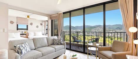Una sala moderna con sofá, sillón, mesa de centro y un balcón con vistas.