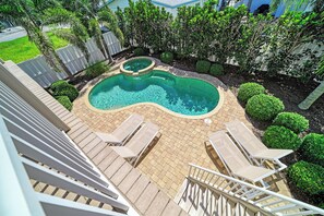 A swimming pool with a unique shape, surrounded by a brick deck and equipped with lounge chairs. - Still Waters hosted by Beach Retreats FL (Holmes Beach)