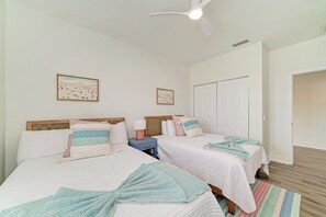 A hotel room with two beds, a ceiling fan, and two framed pictures on the wall. - Still Waters hosted by Beach Retreats FL (Holmes Beach)