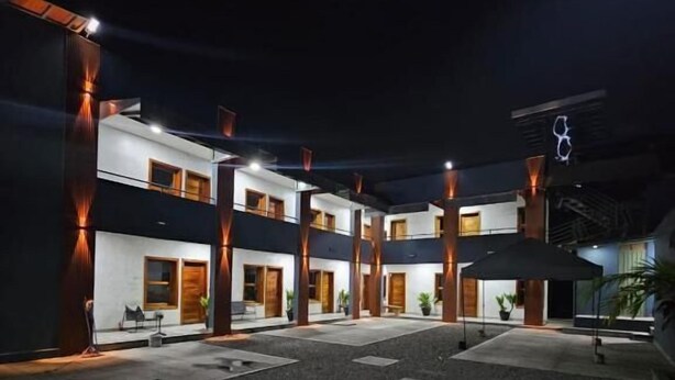 Un edificio moderno de varios pisos, con amplios ventanales y un patio con piso de concreto.