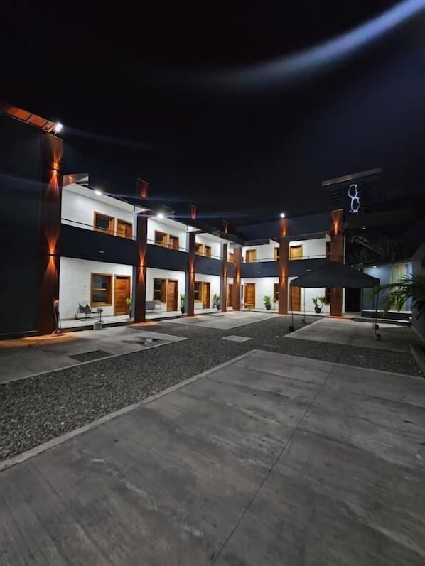 A modern building with multiple floors, large windows, and a courtyard with a concrete floor.