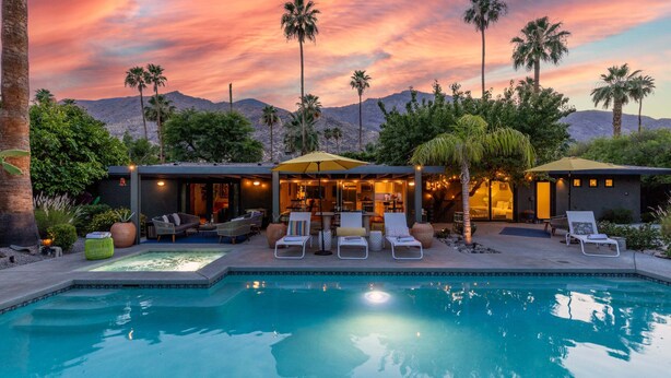 A poolside area with lounge chairs, a pool, and a building with outdoor lighting. - Sol y Soledad: A Modern Palm Springs Retreat with Private Pool, Spa & Office (Palm Springs)