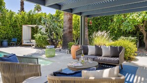An outdoor patio area with wicker furniture, a round table, and a seating arrangement. - Sol y Soledad: A Modern Palm Springs Retreat with Private Pool, Spa & Office (Palm Springs)
