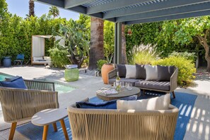 Ein möblierter Patio mit Korbmöbeln, einem runden Tisch und Sitzgelegenheiten.