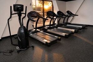 A gym with treadmills, a stationary bike, and a rowing machine.