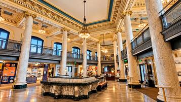 Un hall espacioso con columnas de mármol, una fuente central y un entresuelo con balcones.