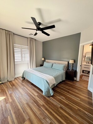 A bedroom with a bed, a ceiling fan, a nightstand, a lamp, and a window with curtains. - Modern Home Escape in the Pines - Family Friendly (Show Low)