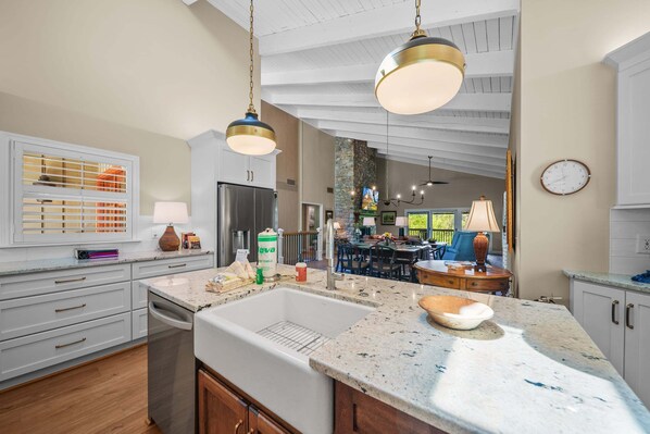 A kitchen with a large island, white cabinetry, and pendant lighting.