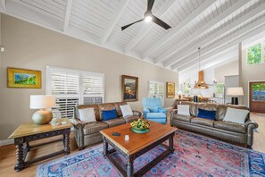 A spacious living room with a high ceiling, two sofas, a coffee table, and a patterned rug.