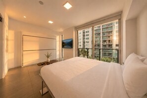 Une chambre moderne avec un grand lit, une télévision et un balcon offrant une vue sur la ville.
