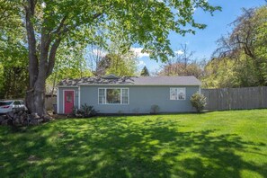 A single-story house with a red door, white windows, and a small front yard. - Pop, Bubble, and sun-drenched Cutie Cottage! (Middletown)