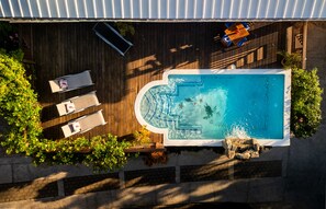 An aerial view of a swimming pool with a wooden deck, lounge chairs, and a small waterfall feature. - Blue Orchid- Ocean Advantage (Roatan)