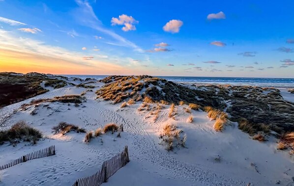 Ein Strand mit Dünen und einem Holzzaun.