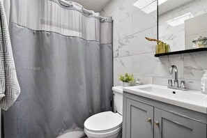 Ein Badezimmer mit Duschvorhang, Toilette, Waschbecken und Spiegel.