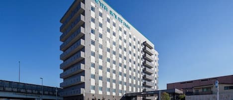 A multi-story hotel with a modern design, featuring a prominent entrance and a parking area.