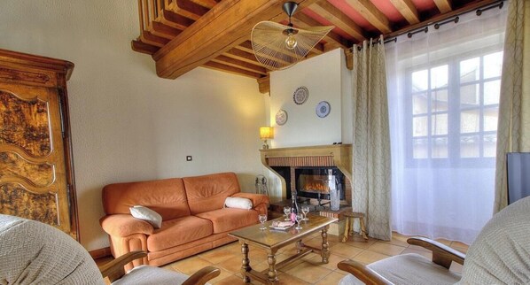 A living room with a sofa, a coffee table, a fireplace, and a television. - Le Camelia - CHENAS - Gîte (CHENAS)