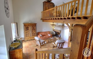 A spacious living area with a wooden staircase, a sofa, two armchairs, a cabinet, and a fireplace. - Le Camelia - CHENAS - Gîte (CHENAS)