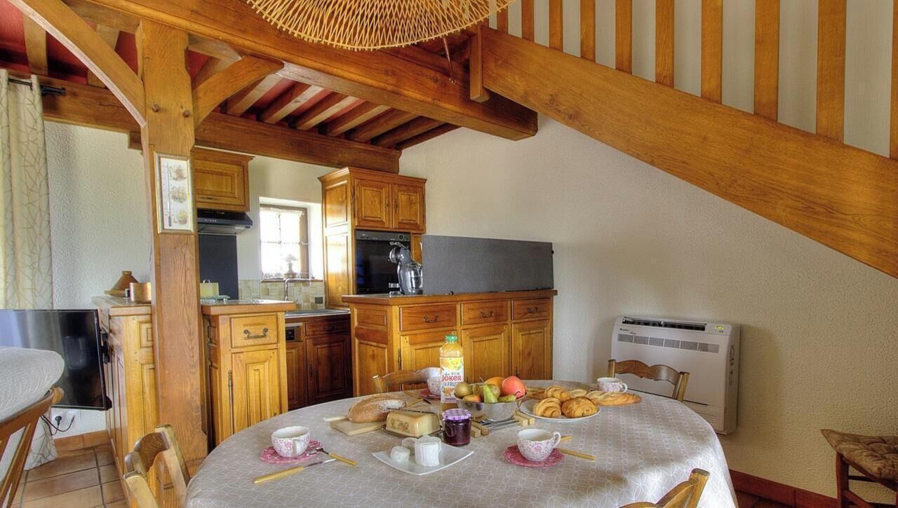 Une cuisine chaleureuse avec des meubles en bois, une table à manger dressée et un luminaire suspendu.