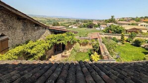 A stone building with a sloped roof and a garden with a view of a rural landscape. - Bird Paradise (POMMIERS)
